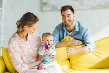 Smiling parents and infant daughter playing with plastic block