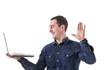 young programmer (man) holding a laptop in hands and talking on skype with friends isolated on...