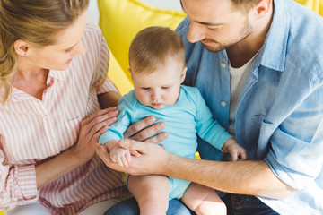 Young parents holding infant daughter in hands