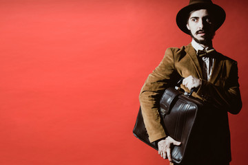 man posing in studio with suitcase in hands