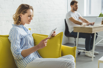 Smiling woman with digital tablet and man typing on laptop