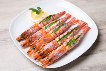 Baked langoustines on a white plate. Selective focus, close-up.