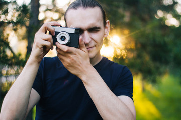 Handsome guy with a retro camera. A film camera in the hands of a young photographer. Model on the...