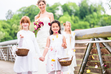 Wedding couple bride and groom with flower children or bridesmaid in white dress and flower baskets