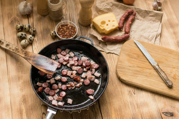 Bavarian sausages are sliced and fried in a frying pan.