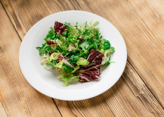 Vegetarian salad with fresh vegetables. The process of mixing vegetables.