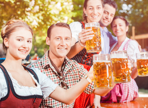 Im Biergarten - Freunde in Lederhosen und Dirndl trinken eine frische Maß Bier