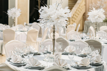 Little round white tables decorated with grey clothes and white centerpieces for wedding dinner