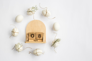 Easter white eggs are minimalistically decorated with twine and gypsophila. With a wooden calendar....