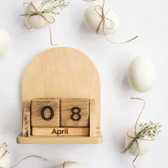 Easter white eggs are minimalistically decorated with twine and gypsophila. With a wooden calendar....