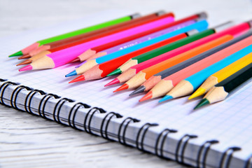Obraz premium Color pencils lying on a pad with a spiral. Gray natural background, blur