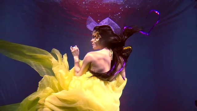 a young woman in a magnificent dress dances under the water in a lush and bright dress