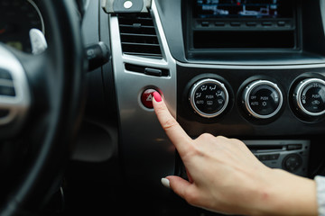 turning on car air conditioning system,finger hitting car emergency light botton,Hand tuning fm radio button in car panel.