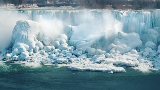 A wall of ice and snow on the Niagara Falls. Beautiful winter landscape in a popular place among tourists. Nature of the USA and Canada. 4K 10 bit video