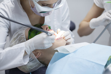 Naklejka premium Doctor dentist treats teeth of a beautiful young girl patient. The girl on reception at the dentist. Doctor dentist treats tooth.