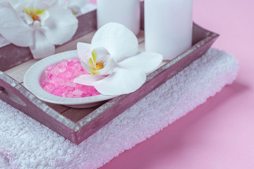 Obraz na płótnie Canvas Spa background, flat lay layout with pink sea salt, candles and aroma oils and cosmetic care products on a pink background