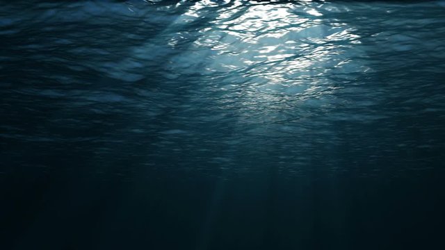 Underwater sea waves, with light sun rays. Dark blue water surface.