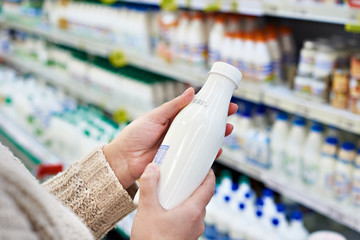 Buyer hands with bottle of milk at grocery