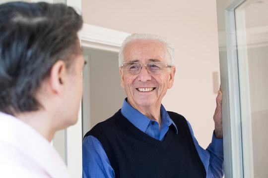 Man Checking On Elderly Male Neighbor