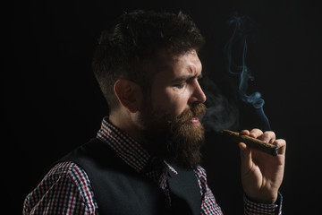 Bearded man with cigar. Barber shop. Fashionable bearded men. Smoldering cigars. Smoke from cigar. Classical vintage male portrait. Silhouette of gentleman in checkered shirt, waistcoat smoking cigar.