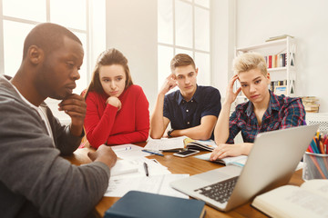 Obraz premium Group of diverse students studying at wooden table