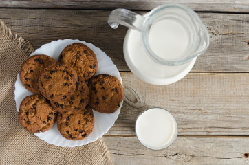 Biscuits, a jug and a glass of milk on burlap, on the old table.The view from the top.