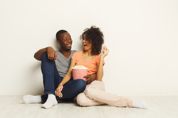 Fototapeta na wymiar Smiling black couple wathing movie at home