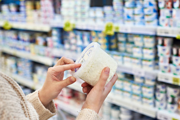 Buyer hands with cottage cheese in grocery