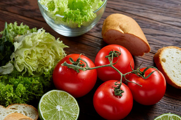 Healthy breakfast with tomatoes, letucce, lime on wooden background, close-up, selective focus, top view.