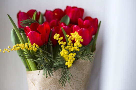 A lovely bunch of red tulips and yellow mimose are in vase