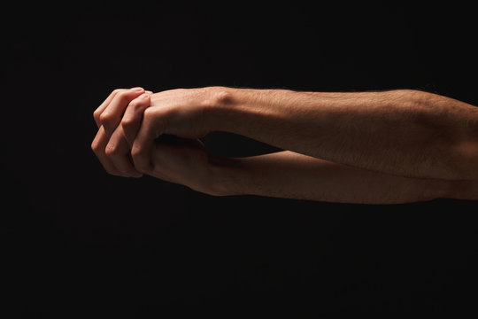 Man holding hands together at black isolated background
