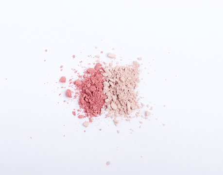 Crushed eyeshadows, blushes or powders scattered on white background. Copy space. Flat lay. Top view