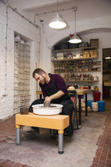 Male artist makes clay pottery on a spin wheel