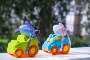 Two Easter cars tied up with colored ribbons go on the table on the background of greenery