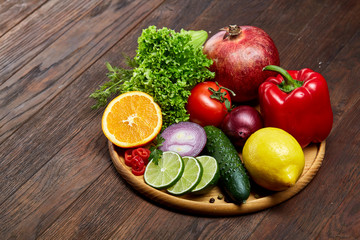 Still life of fresh organic vegetables on wooden plate over wooden background, selective focus, close-up