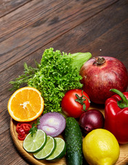 Still life of fresh organic vegetables on wooden plate over wooden background, selective focus, close-up