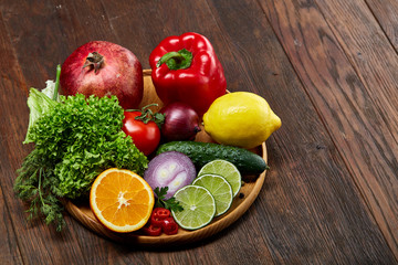 Still life of fresh organic vegetables on wooden plate over wooden background, selective focus, close-up