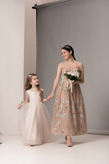Fototapeta na wymiar Little pretty girls with flowers dressed in wedding dresses