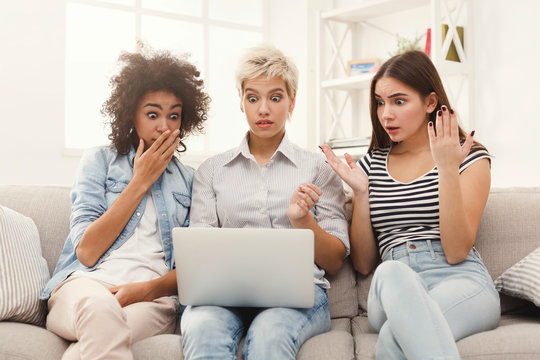 Three beautiful shocked women using laptop at home