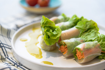 Thai healthy food : Close up of homemade mixed fresh vegetable salad roll in noodle on white dish with  seafood dipping sauce.