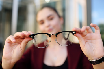 young girl holding glasses close-up. Optics, blzorukost, farsightedness, astigmatism.
