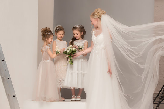 Little pretty girls with flowers dressed in wedding dresses