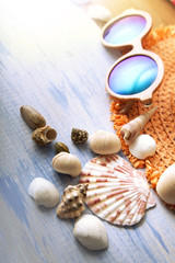 beach accessories glasses hat cockleshells on wood deck.