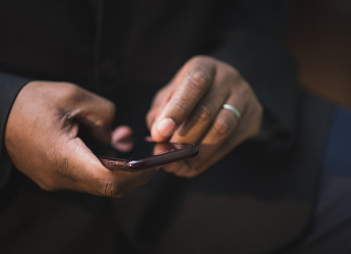 African American Man In Black Suit Using Mobile Device