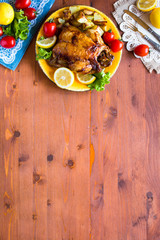 Fototapeta na wymiar Homemade baked chicken with lemon and potatoes on a wooden background