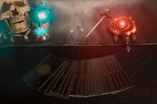 Tarot card / Tarot card, skull and crystal ball on the table with smoke under candlelight. Dark tone.