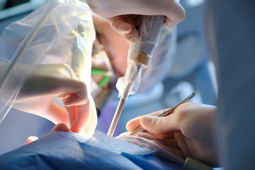 Hands of a dental surgeon in protective gloves with a tool during surgery
