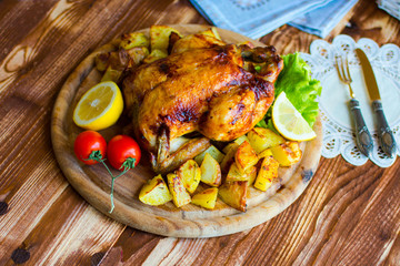 Homemade baked chicken with lemon and potatoes on a wooden background
