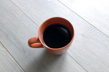 Orange coffee cup on the table close-up blurred background