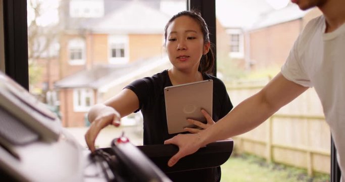 4K Female fitness instructor working with male client at the gym. Slow motion.
